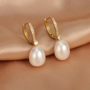 Close-up of 18K gold-plated earrings with freshwater pearls and sparkling zircon pavé
