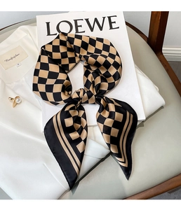 Detail of checkered silk scarf knotted on a white shirt with elegant glossy texture