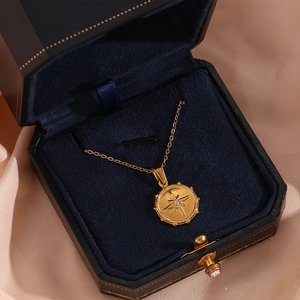 Detail of gold starburst pendant with white zircon in a blue velvet jewelry box