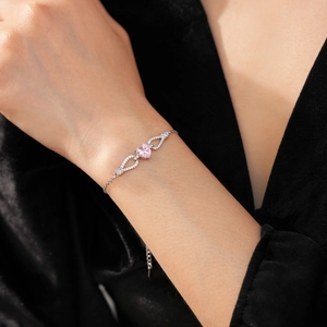 Detailed view of silver heart bracelet with pink zircon and micro-pave stones on model