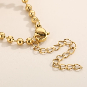 Close-up of golden beaded necklace with spring clasp and adjustable extender chain link