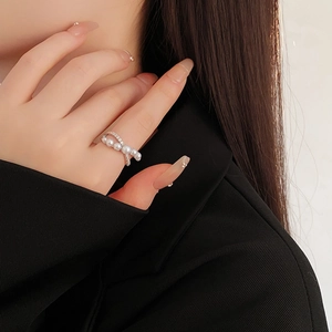 Macro shot of an elegant pearl row ring with silver band and zircon accents on a finger