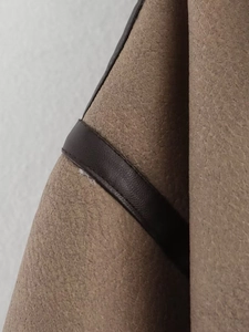 Macro detail of brown suede jacket showing leather piping and faux shearling lining texture