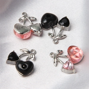 Detail of pink and black cherry heart pendants on grey silk for DIY jewelry making