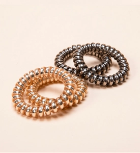 Close-up of metallic spiral telephone wire hair ties in rose gold and gunmetal finish