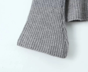 Gros plan des poignets en maille côtelée grise sur un pull vintage montrant la texture