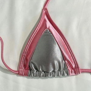 Macro detail of glossy silver bikini top with pink metallic trim and precision stitching