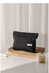 Close-up of black lace fabric texture and brand label on a canvas cosmetic storage bag
