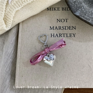 Macro detail of silver heart pendant with embossed bow and pink metallic ribbon