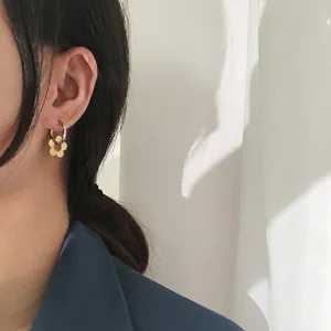 Daisy flower earrings with gold petals and silver hoops on a model with artistic shadows