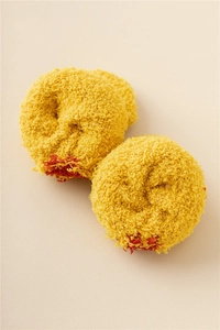 Macro detail of soft yellow coral fleece Christmas socks rolled into a plush ball shape