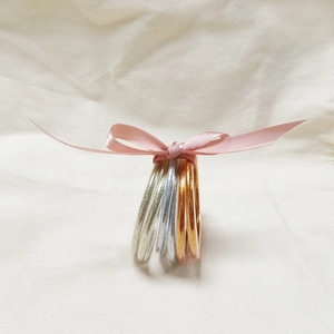 Dettaglio di braccialetti flessibili con glitter e un fiocco decorativo in seta rosa