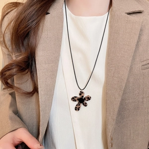 Retro leopard print flower pendant necklace with minimalist black cord on chic blazer