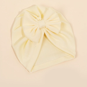 Détail du grand nœud et de la texture côtelée douce du bonnet turban crème pour bébé