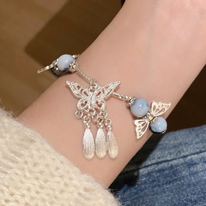 Close-up of a silver beaded bracelet with blue stones and butterfly charms on a wrist