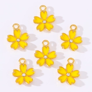 Macro shot of 6 yellow enamel cherry blossom pendants with gold edges and crystal center