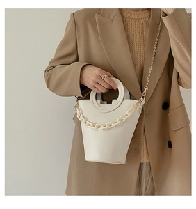 Fashionable beige bucket bag with acrylic chain and ring handle styled on a model