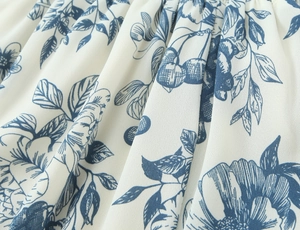 Detailed macro view of vintage blue floral print on light white chiffon fabric