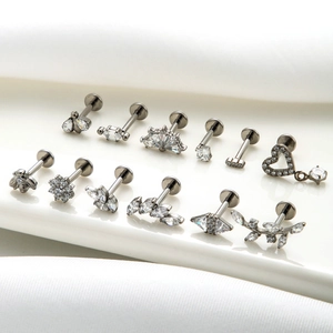 G23 titanium labret studs with zircon bee, flower, and heart shapes on white surface