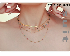 Detail of layered stainless steel gold necklace with colorful beads on model