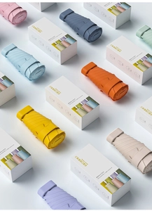 Flat lay of colorful mini pocket umbrellas with compact packaging in various pastel shades