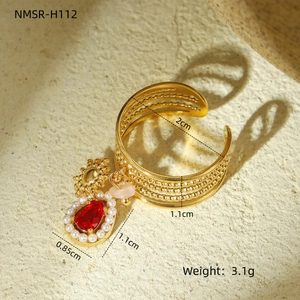 Macro view of gold adjustable ring with red gemstone drop and tiny pearl border