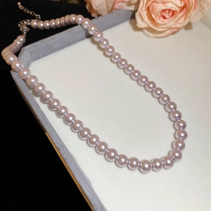 Detail of lavender pearl necklace with silver lobster clasp on grey velvet display