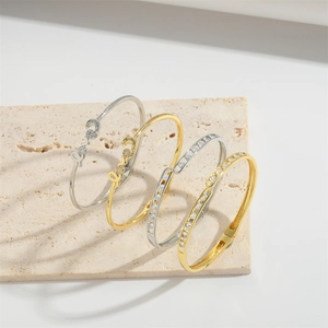 Minimalist love gold and silver bracelets with sparkling zircons on stone background