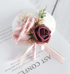Detailed close-up of handmade rose corsage with gold leaves and pink ribbons for weddings