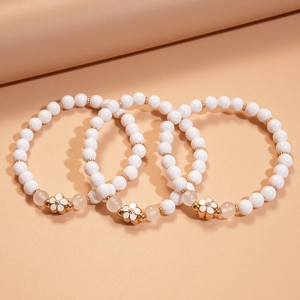 Three-piece set of elegant acrylic beaded bracelets with gold floral pendants