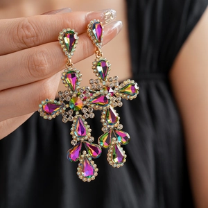 Detailed close-up of a vintage golden cross earring with vibrant multicolored rhinestones