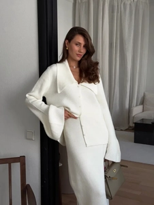 Detailed texture of white knit cardigan and skirt set in a minimalist studio setting