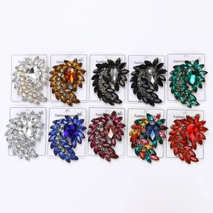 Detailed flat lay of ten crystal teardrop brooches in various colors on display cards