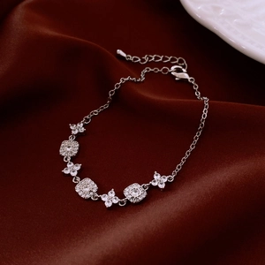 Macro detail of 18K gold plated square and flower charm bracelet with lobster clasp