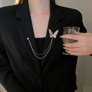 Detailed view of silver butterfly brooch with double chains and pearl on black blazer