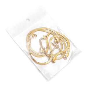 Detailed view of an 18K gold snake bone chain necklace with a heart pendant in a clear bag