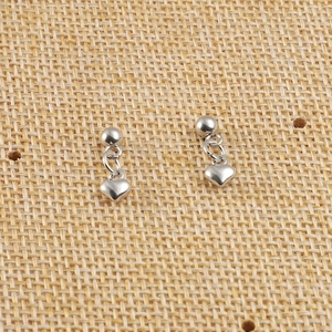 Gros plan de boucles d'oreilles en acier inoxydable avec pendentifs en cœur