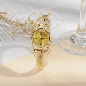 Detailed close-up of a vintage-style gold bangle watch with a Roman numeral dial
