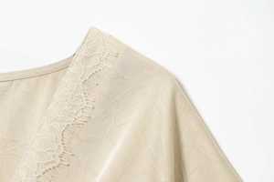 Close-up of elegant lace neckline and glossy satin fabric on a beige midi dress