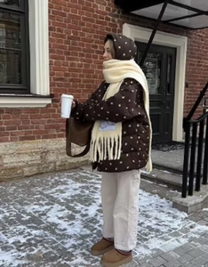 Detail of brown polka dot puffer jacket with a cozy white fringed scarf in winter