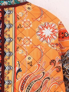 Detailed macro view of diamond quilted orange jacket with colorful paisley floral patterns