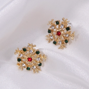 Detail of snowflake earring with red, green and white rhinestones on white silk