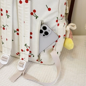 Close-up of side zipper pocket on white corduroy cherry backpack with smartphone storage