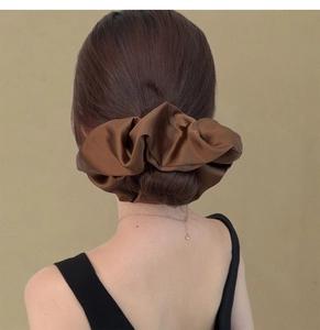 Detail of oversized dark brown satin scrunchie styled on a classic hair bun