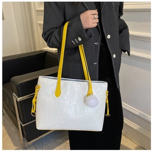 Detail of white embossed tote bag with yellow contrast strap and white pompom charm
