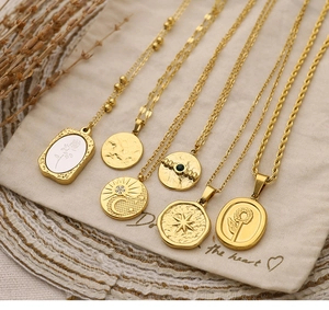 Detail of six vintage gold-plated necklaces with rose, star, and moon charms on linen bags