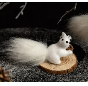 Close-up of a white plush squirrel ornament with a fluffy tail and pinecone on a wood base