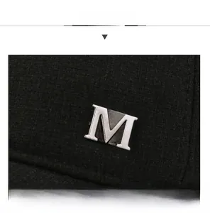 Detail van het zilveren metalen M-logo op de zwarte stof van de winterpet