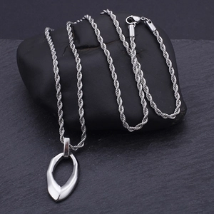 Close-up of vintage silver irregular drop pendant with textured twist chain on stone