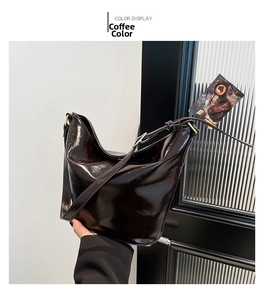 Detail of coffee brown shoulder bag featuring glossy wrinkled leather and metal buckles